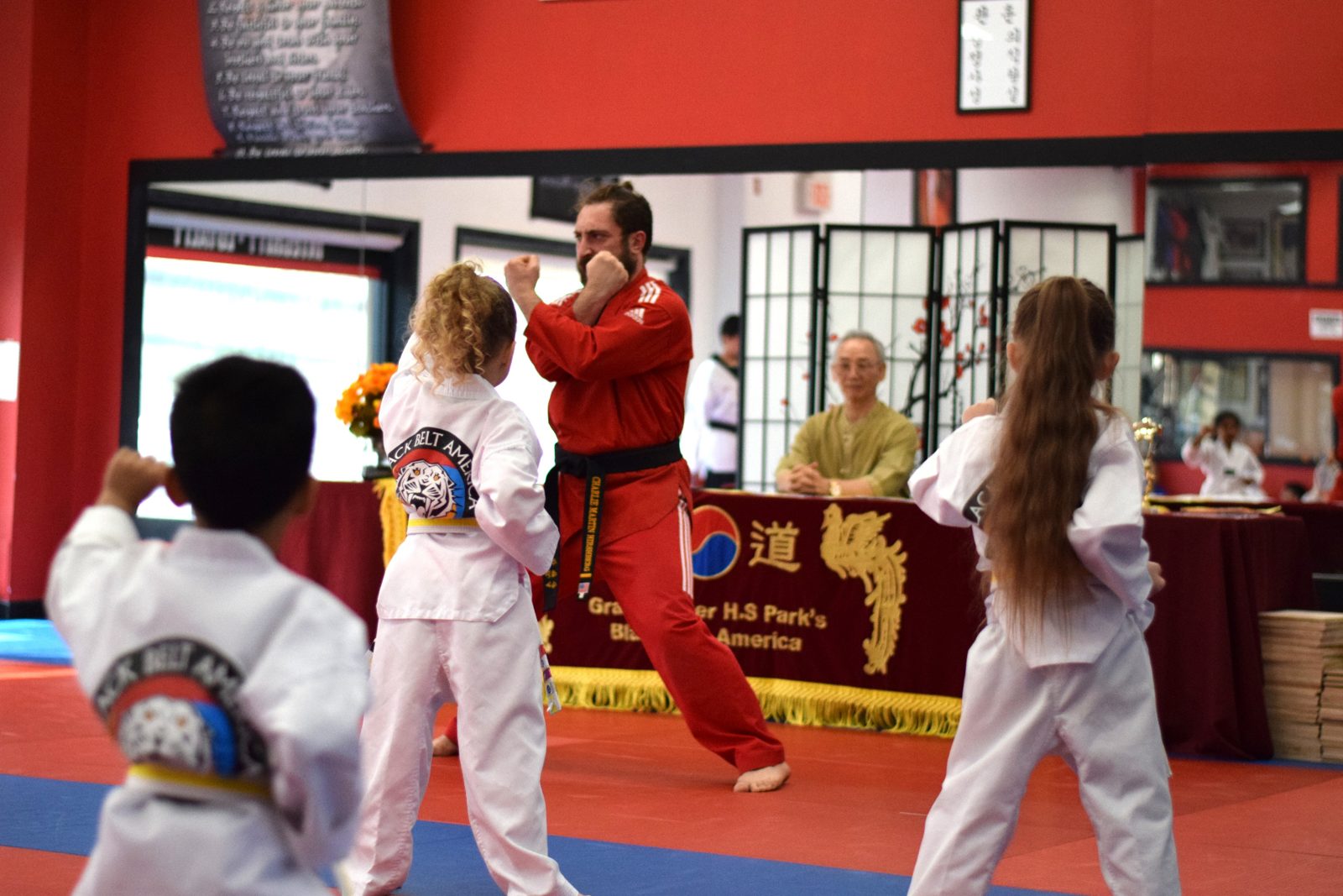 Instructor leading young students in sparring stance demonstration